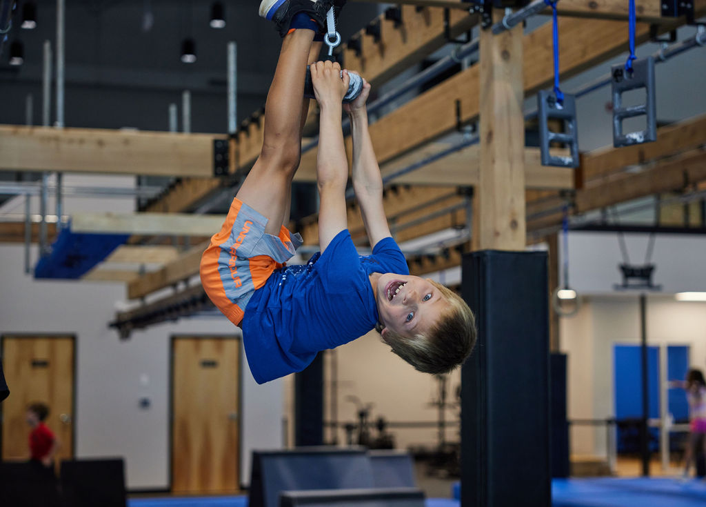 kid holding onto rings at an indoor facility