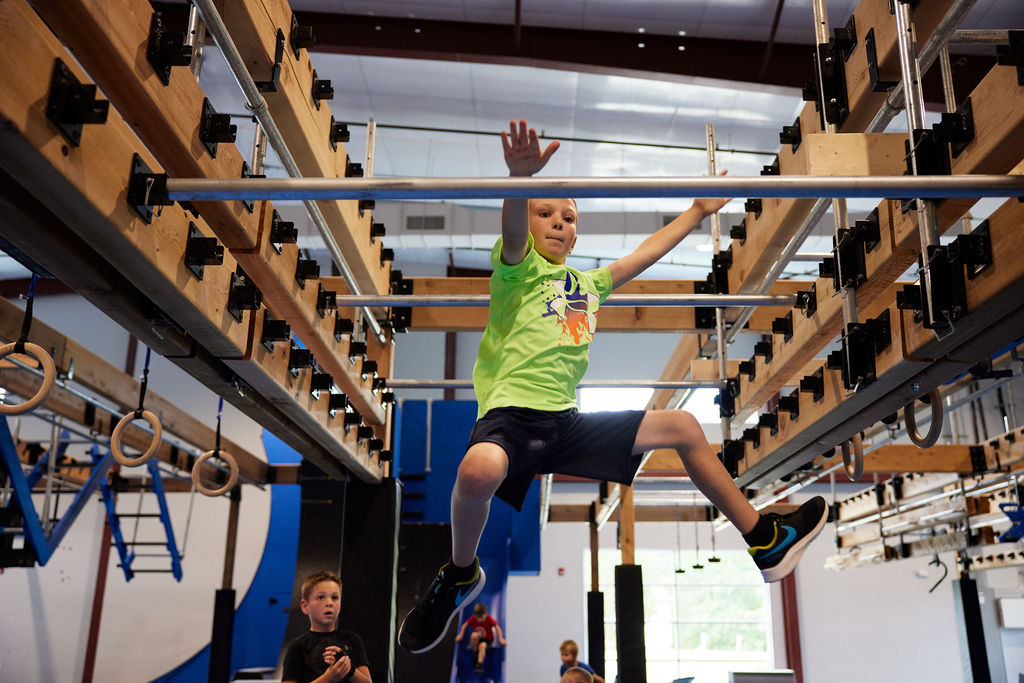 kid playing on monkey bars in indoor facility