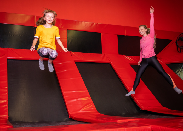 two kids jumping on trampoline indoors