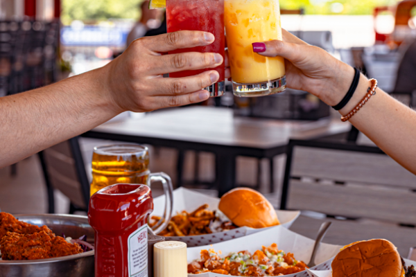 Two people cheerings drinkss at Tap Station